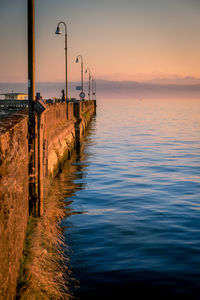 Empty pier on lake at sunset