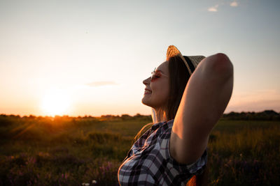 Young woman standing on land against sky during sunset