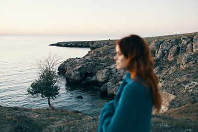 Side view of woman looking at sea against sky