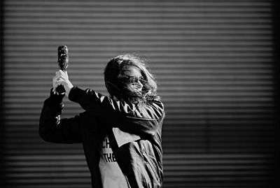 Woman holding baseball bat while standing against shutter