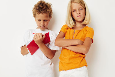 Portrait of smiling girl with brother against white background