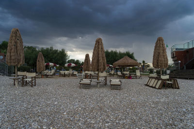 Empty chairs on beach against sky