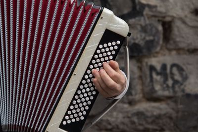 Cropped hand playing musical instrument against wall