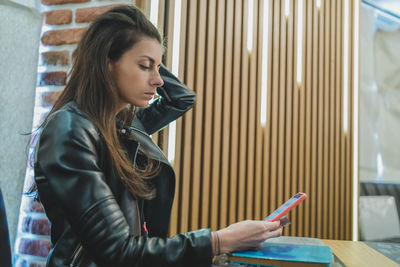 Side view of young woman using mobile phone