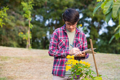 Woman holding umbrella standing against plants