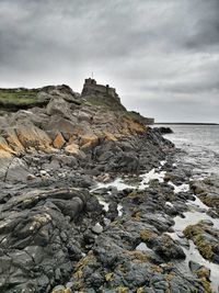 Rock formations on beach against sky