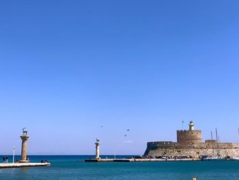 Sea by buildings against clear blue sky