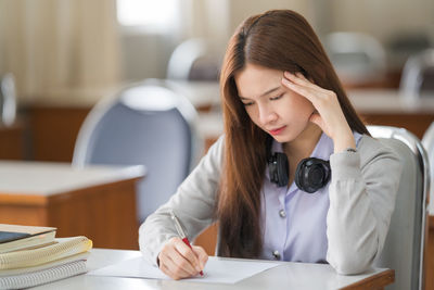 Young woman looking down while sitting on table