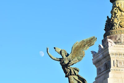 Low angle view of angel statue against blue sky