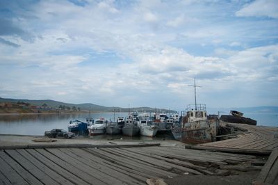 Boats moored at harbor against sky