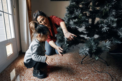 Grandparents decorate the christmas tree with their little granddaughter