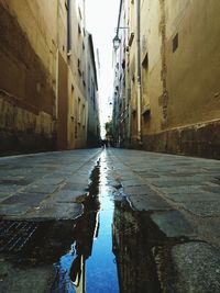 Wet street amidst buildings in city