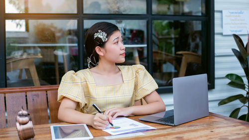 Young woman using mobile phone while sitting on table