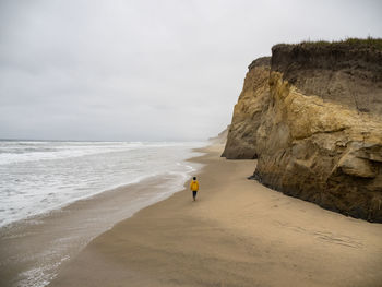 Lone young person walking along deserted california beach on gray day