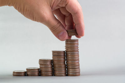Cropped image of hand holding coin stack against white background