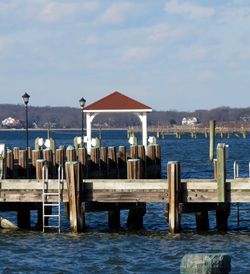 Wooden posts on pier by sea against sky