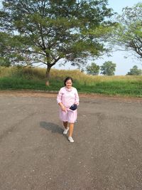 Full length portrait of woman standing on road