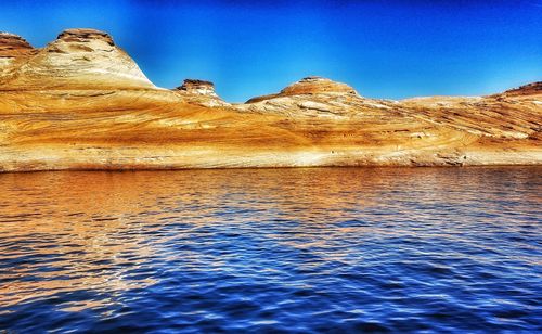 Scenic view of sea and mountains against clear blue sky