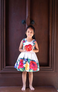 Portrait of a smiling girl standing against door