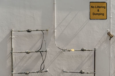 Low angle view of telephone pole against wall