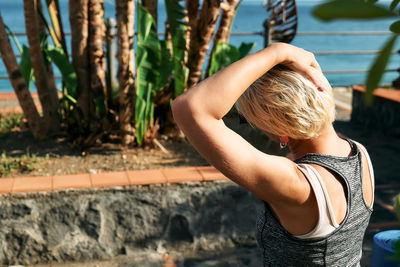 Sporty blond woman in sportswear stretching neck muscles after workout outdoors. fitness, sport.