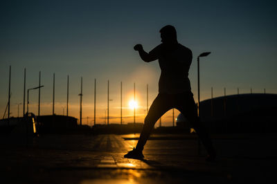 Silhouette woman standing against sky during sunset