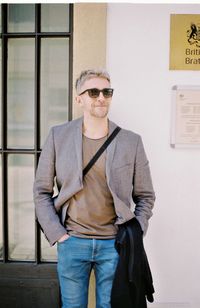 Portrait of man wearing sunglasses standing against wall