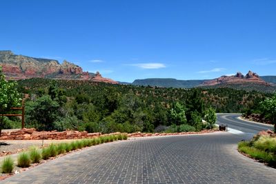 Road by mountain against clear blue sky