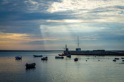 Sailboats in sea against sky at sunset