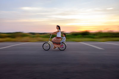 Man with bicycle on road against sky