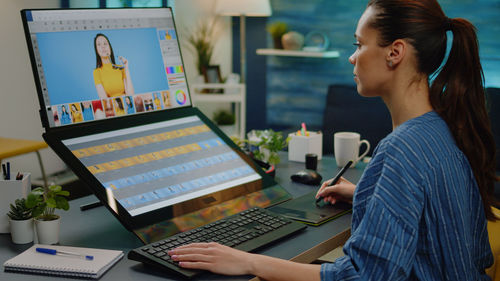 Side view of woman using laptop while sitting on table