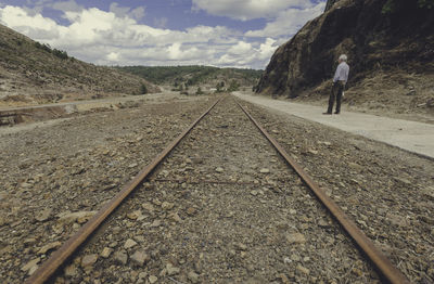 Rear view of man standing by railroad track