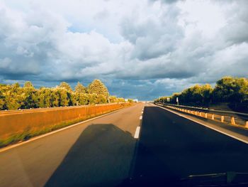 Road by trees against sky