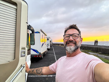 Portrait of senior man standing against car