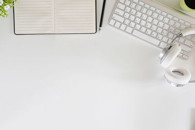 High angle view of computer keyboard and book on white background