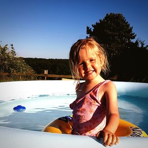 Portrait of cute girl wearing inflatable ring while standing in wading pool