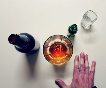 Cropped hand by beer glass against white background