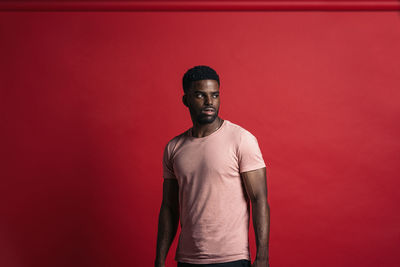 Portrait of young man standing against red background