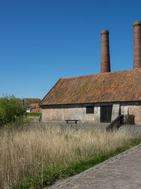 Old building on field against clear blue sky