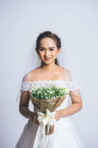 Portrait of a smiling young woman standing against white wall