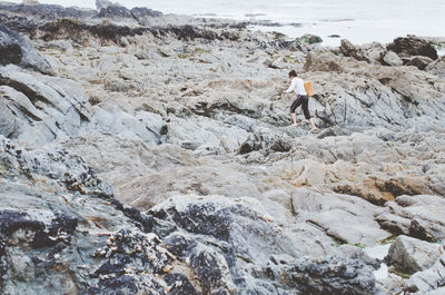 Woman walking on rock formation at beach