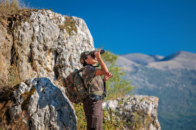 Observation of wild animals in nature. woman with binoculars in the mountains.