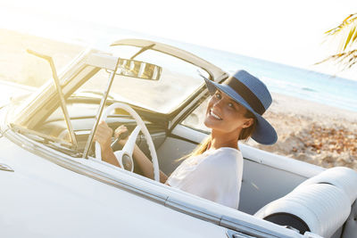 Side view of young woman sitting in car