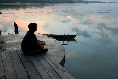 Rear view of people sitting on pier