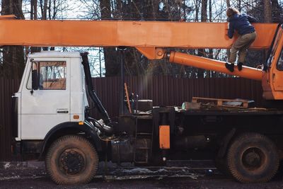 Rear view of man climbing on orange crane