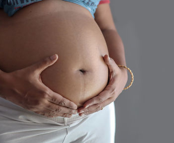 Midsection of woman touching face against black background