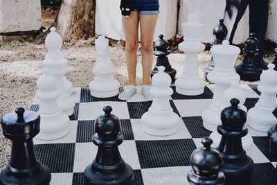 Low section of woman standing on chess board at park