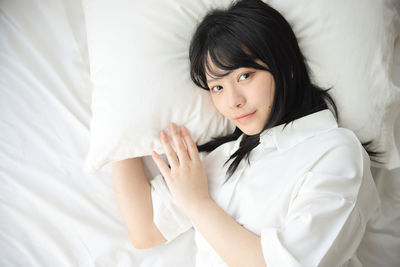 Portrait of young woman sitting on bed at home