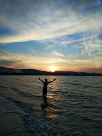 Silhouette man on beach against sky during sunset