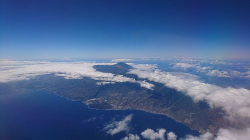 Aerial view of snowcapped mountain against blue sky